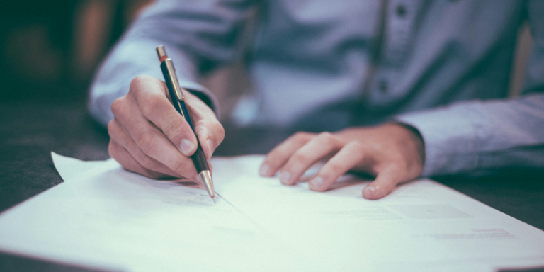 picture of a person signing a paper with a pen